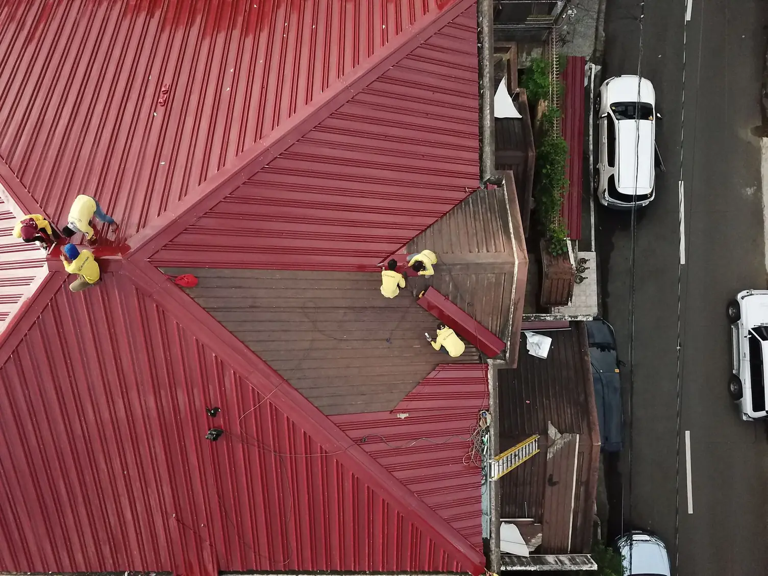 Vue aérienne d'un chantier de couverture métallique rouge avec deux intervenants