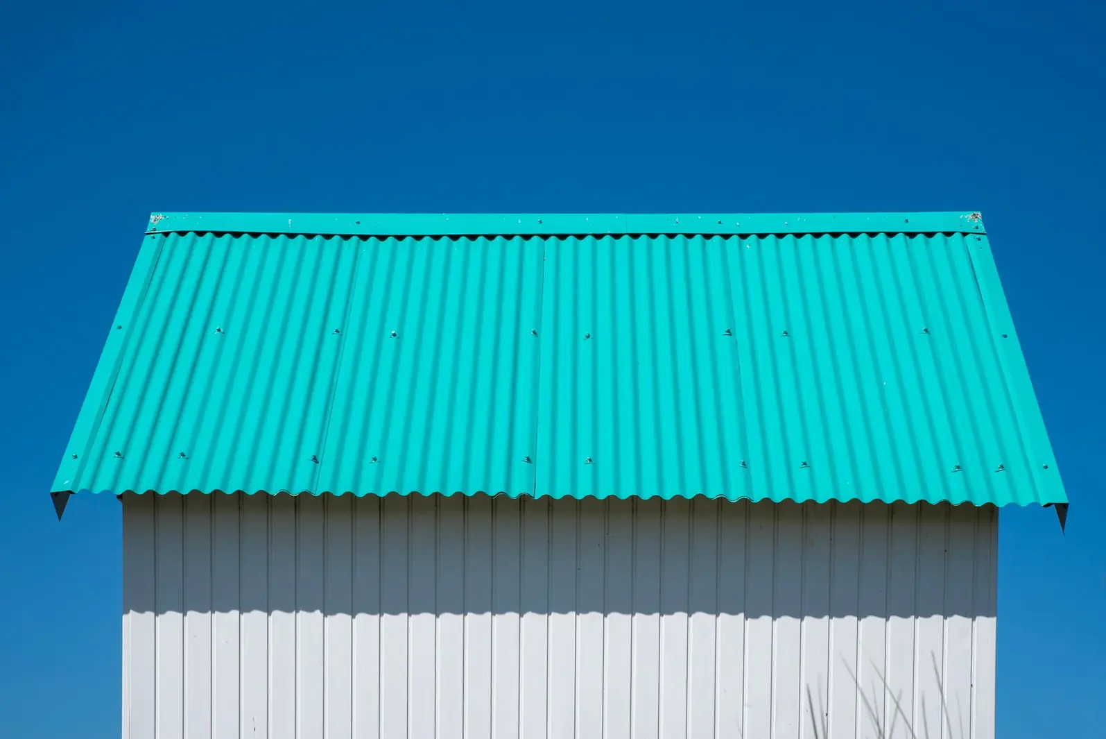 Petite construction couverte en tôle ondulée turquoise sous un ciel bleu