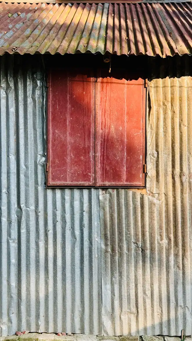 Mur de tôle ondulée ancienne avec un volet de bois rouge