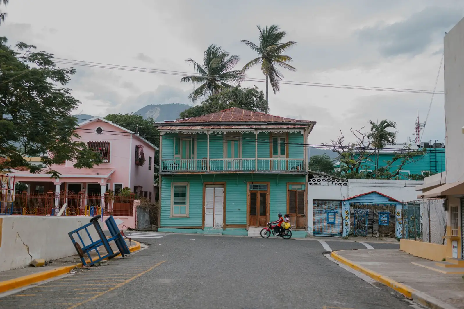 Rue d'un bourg antillais bordée de maisons colorées et de palmiers