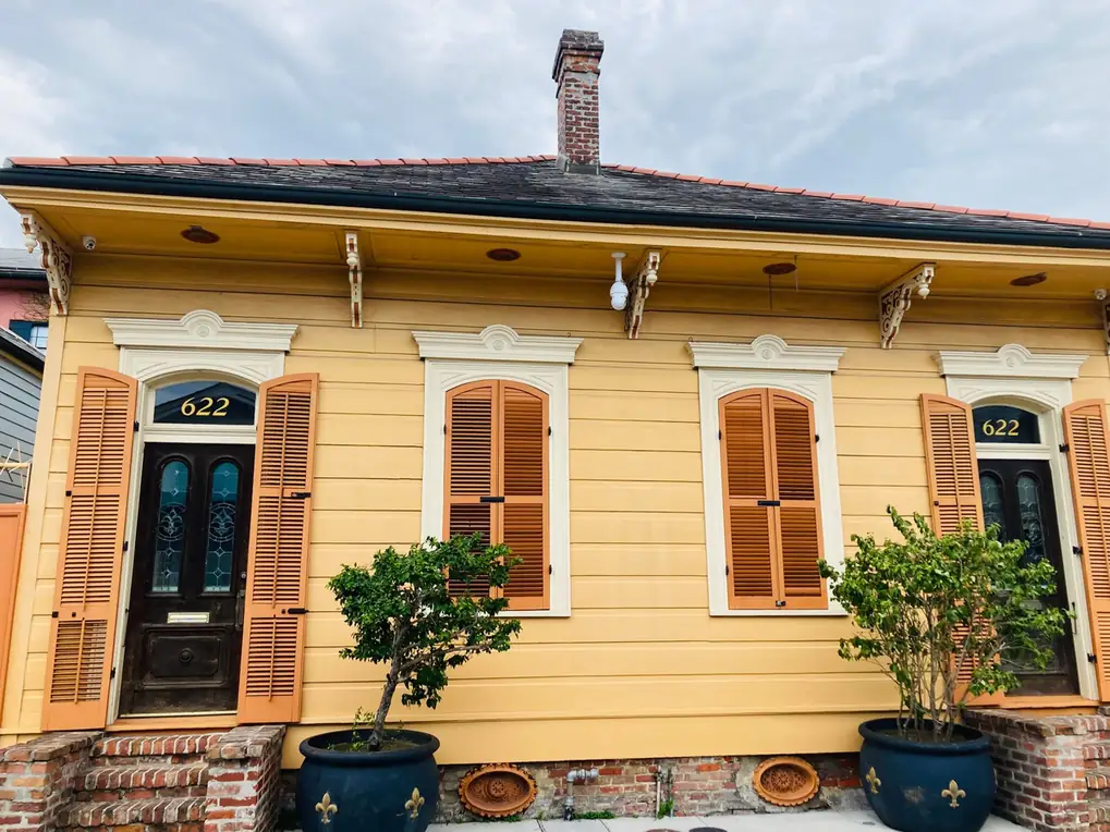 Façade créole jaune à volets de bois et débord de toiture