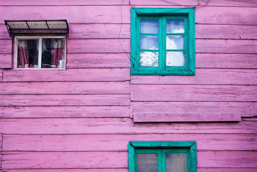 Bardage de bois peint en rose avec fenêtres turquoise